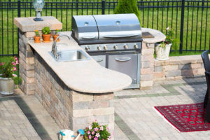 Beautiful outdoor kitchen constructed from paver stones. Built-in grill and sink areas